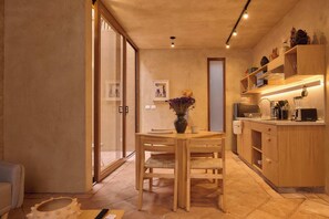A modern kitchen with wooden cabinets, a dining table, and a vase with flowers. - Casona Xochimilco - Trinidad (Oaxaca de Juárez)