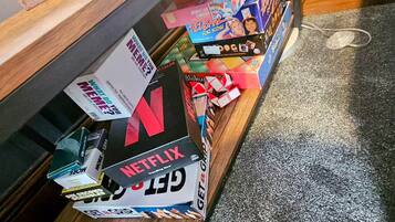 Una estantería con distintos juegos de mesa y un reproductor de Netflix.