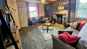 A cozy living room with a fireplace, dark walls, and a wooden ceiling. - 3 bedroom cottage in the heart of Bingley (Bingley)