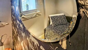 A room with a round mirror on the wall, a patterned pillow, and a wall with animal prints. - 3 bedroom cottage in the heart of Bingley (Bingley)