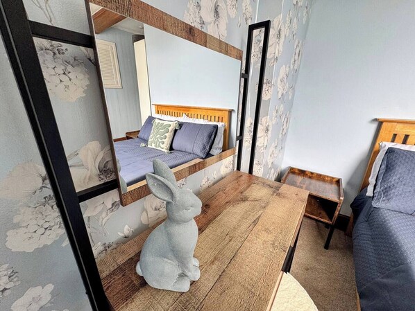 Un dormitorio con una cama litera, una mesa de madera, una silla pequeña y una figurita de conejo.