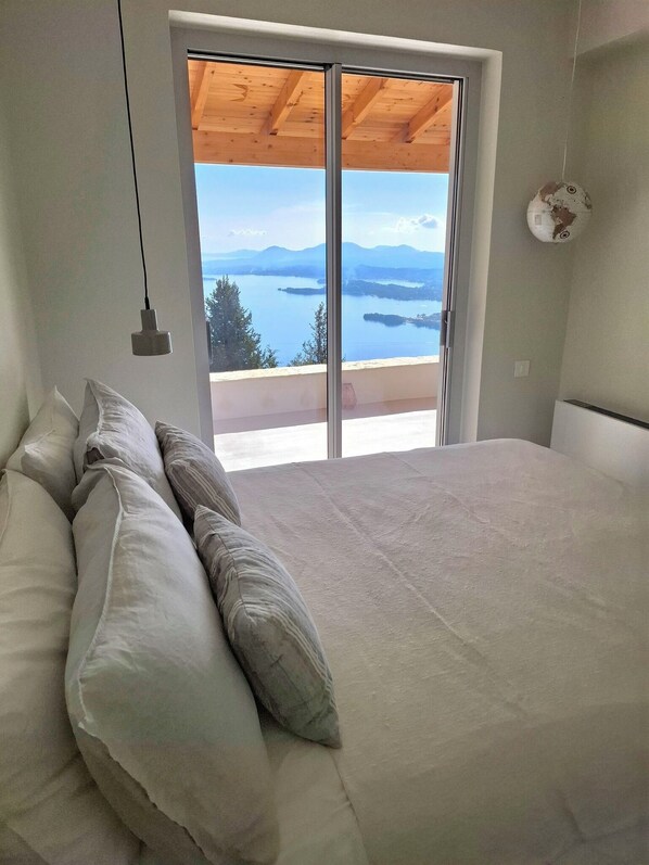 Een slaapkamer met een groot bed, uitzicht op een meer en een houten plafond.