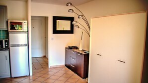 Eine Küche mit Kühlschrank, Mikrowelle und Schränken. Eine Tür führt in einen anderen Raum.