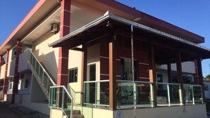 A building with a covered entrance, a staircase, and a glass railing.