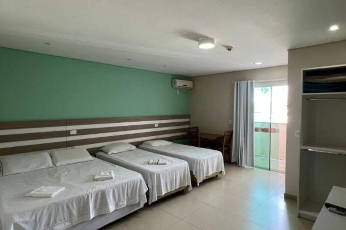Une chambre d’hôtel avec deux lits simples, un bureau, une chaise et une porte-fenêtre coulissante donnant sur l’extérieur.
