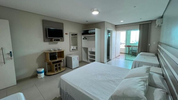 A hotel room with a large bed, a TV, a wardrobe, and a desk.