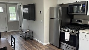 A modern kitchen with stainless steel appliances, a dining area with a wooden table and chairs, and a large window providing natural light.