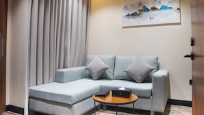 Uma sala de estar moderna com um sofá seccional azul claro, uma pequena mesa de centro de madeira e uma pintura de montanhas na parede.