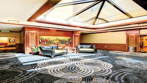 Un'hall d'albergo con soffitto alto, un lucernario e una moquette decorata.