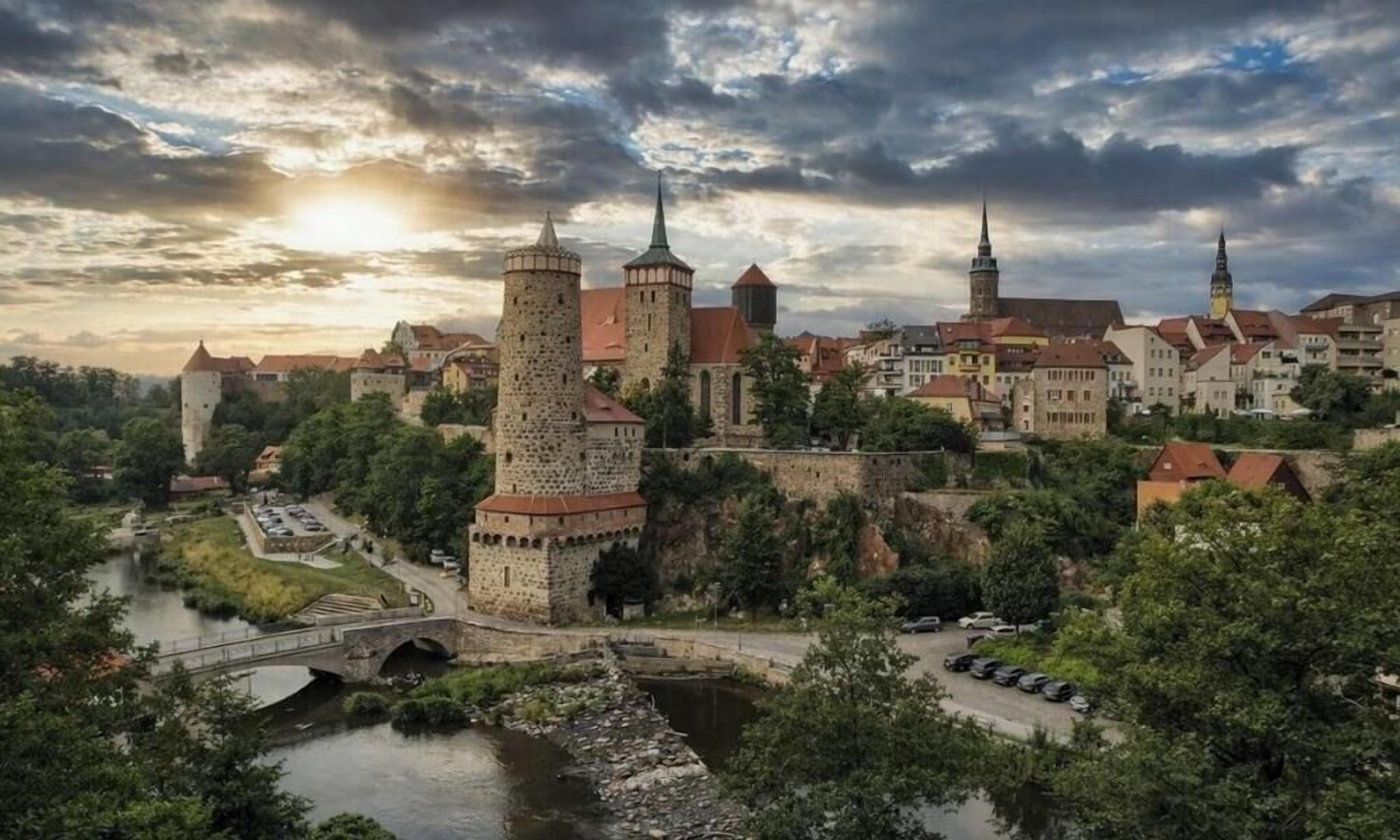 Uma cidade histórica com arquitetura medieval, incluindo uma torre imponente e uma igreja com um campanário.