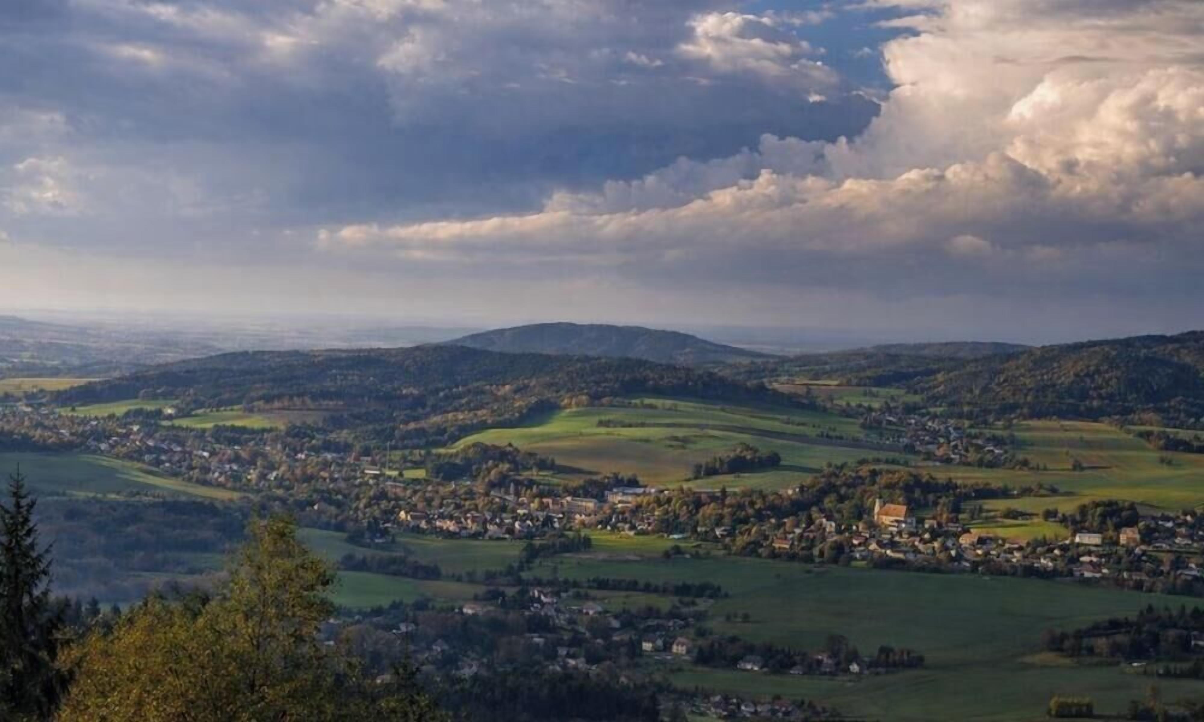 A panoramic view of a town nestled in a valley with rolling hills in the background.