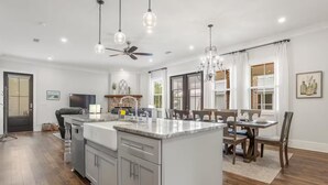 A modern kitchen with a central island, built-in appliances, and a dining area with a chandelier. - Serene Beach Oasis with Heated Pool (Biloxi)