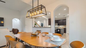 Uma área de refeições com mesa de madeira, cadeiras e um lustre.