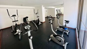 Ein Fitnessraum mit mehreren Ergometer und Laufbändern, einem schwarzen Boden und weißen Wänden.