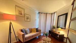 Ein Wohnzimmer mit einer Couch, einer Stehlampe, einem kleinen Tisch mit einer Vase und einem Spiegel an der Wand.