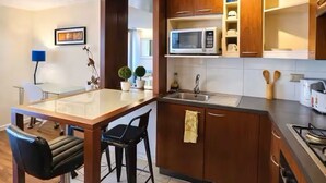 Eine moderne Küche mit Holzschränken, einer Edelstahlspüle, einer Mikrowelle und einem Gasherd.