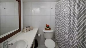 Ein Badezimmer mit Waschbecken, Spiegel, Toilette und einer duschvorhang mit Muster.