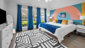 Una camera da letto moderna con un letto grande, una ventola a soffitto, una TV e vista sull'esterno.