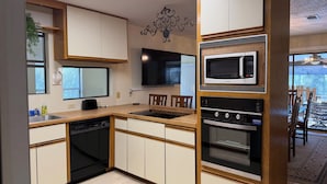Une cuisine moderne avec des meubles en bois, un four à micro-ondes encastré et un lave-vaisselle.