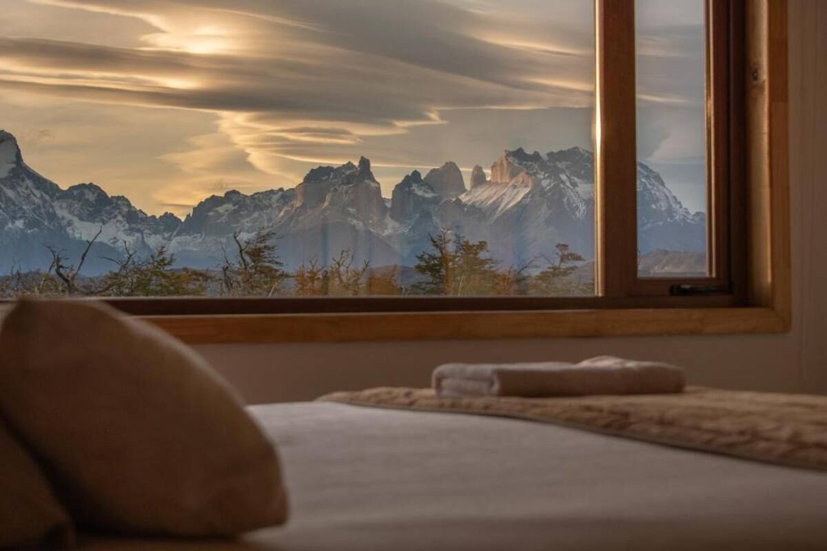 A bedroom with a large window overlooking a mountainous landscape.