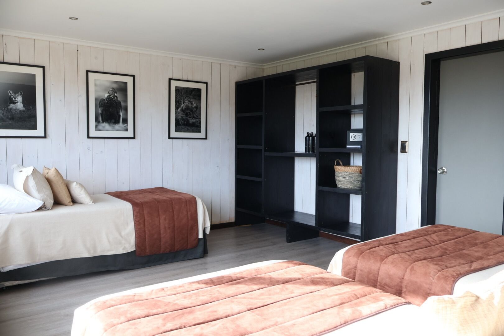 A room with two beds, a wardrobe, and framed pictures on the wall.