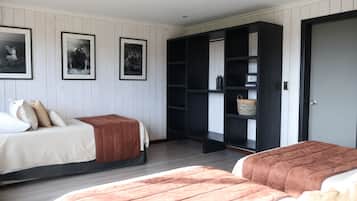 A room with two beds, a wardrobe, and framed pictures on the wall.