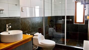 Uma casa de banho moderna com uma sanita, uma pia branca e um cabine de duche.