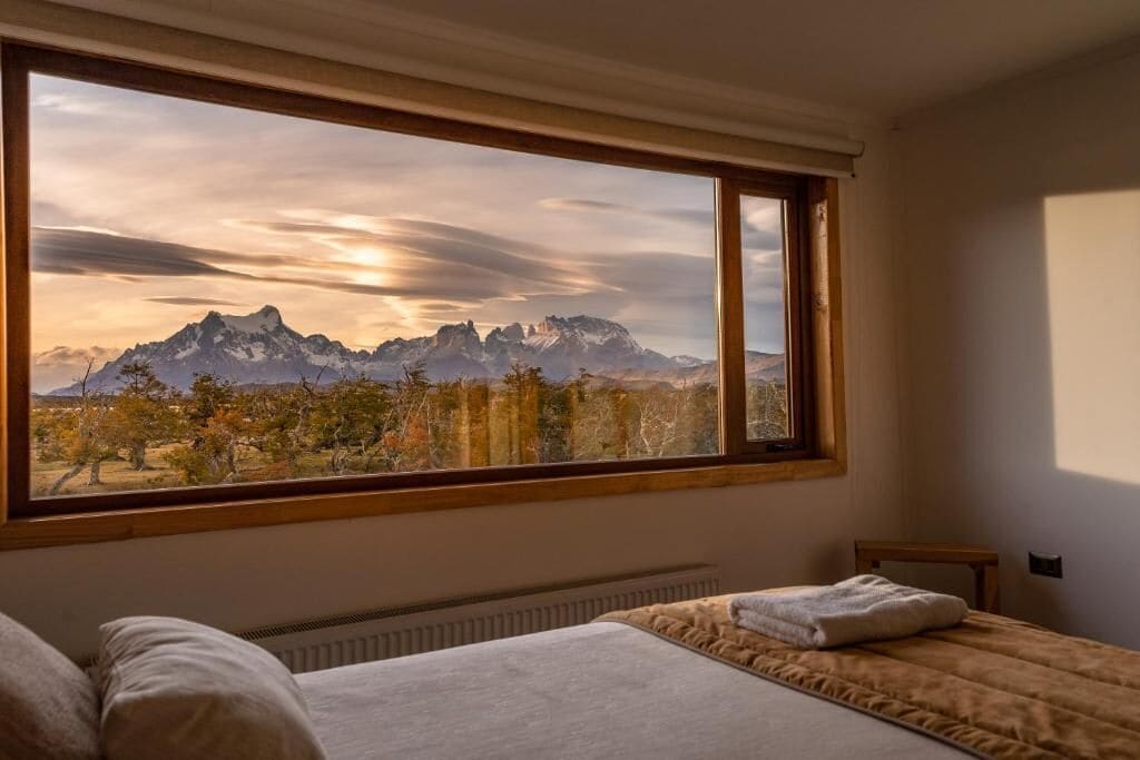 A bedroom with a large window overlooking a mountainous landscape.