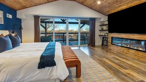 Un dormitorio amplio con una cama grande, un banco, chimenea y vistas al exterior.