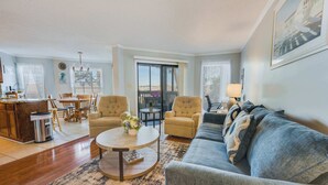 A spacious living room with a sofa, armchairs, a coffee table, and a dining area with a table and chairs. - NEW, Large 2BR in Ocean Greens,Great Location,Pool (North Myrtle Beach)