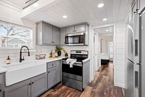 A modern kitchen with grey cabinets, stainless steel appliances, and a wooden floor. - The Resort at Fredericksburg Unit 1 (Fredericksburg)