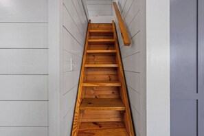 A wooden staircase with a handrail, white walls, and a door on the right. - The Resort at Fredericksburg Unit 9 (Fredericksburg)