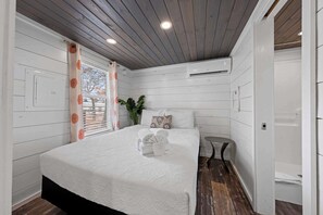 A bedroom with a bed, a small round table, and a window with curtains. - The Resort at Fredericksburg Unit 9 (Fredericksburg)