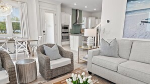 Un salon moderne comprenant un canapé, des fauteuils et un coin repas avec une table et des chaises.