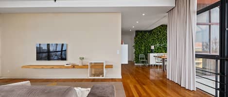 Uma sala de estar moderna com uma janela grande, um sofá, uma TV de tela plana e uma parede verde.