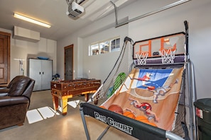 Een recreatieruimte met een tafelvoetbaltafel, een pooltafel en een basketbalspelautomaat.