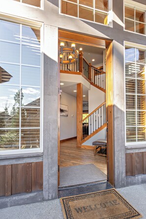 Een modern huis met een houten trap, grote ramen en een deurmat.