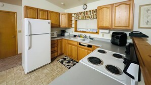 A kitchen with wooden cabinets, a white refrigerator, a microwave, a stove, and a sink.