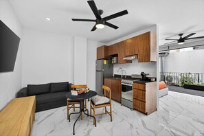 A modern kitchen with wooden cabinets, a dining area with a table and chairs, and a balcony with a railing. - Unit Elote Romantic Zone (Puerto Vallarta)