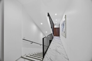 A modern staircase with a black railing, white walls, and a marble floor. - Unit Elote Romantic Zone (Puerto Vallarta)