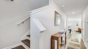 Ein modernes Interieur mit einer Treppe, einem Holzkonsole und einem Essbereich im Hintergrund.