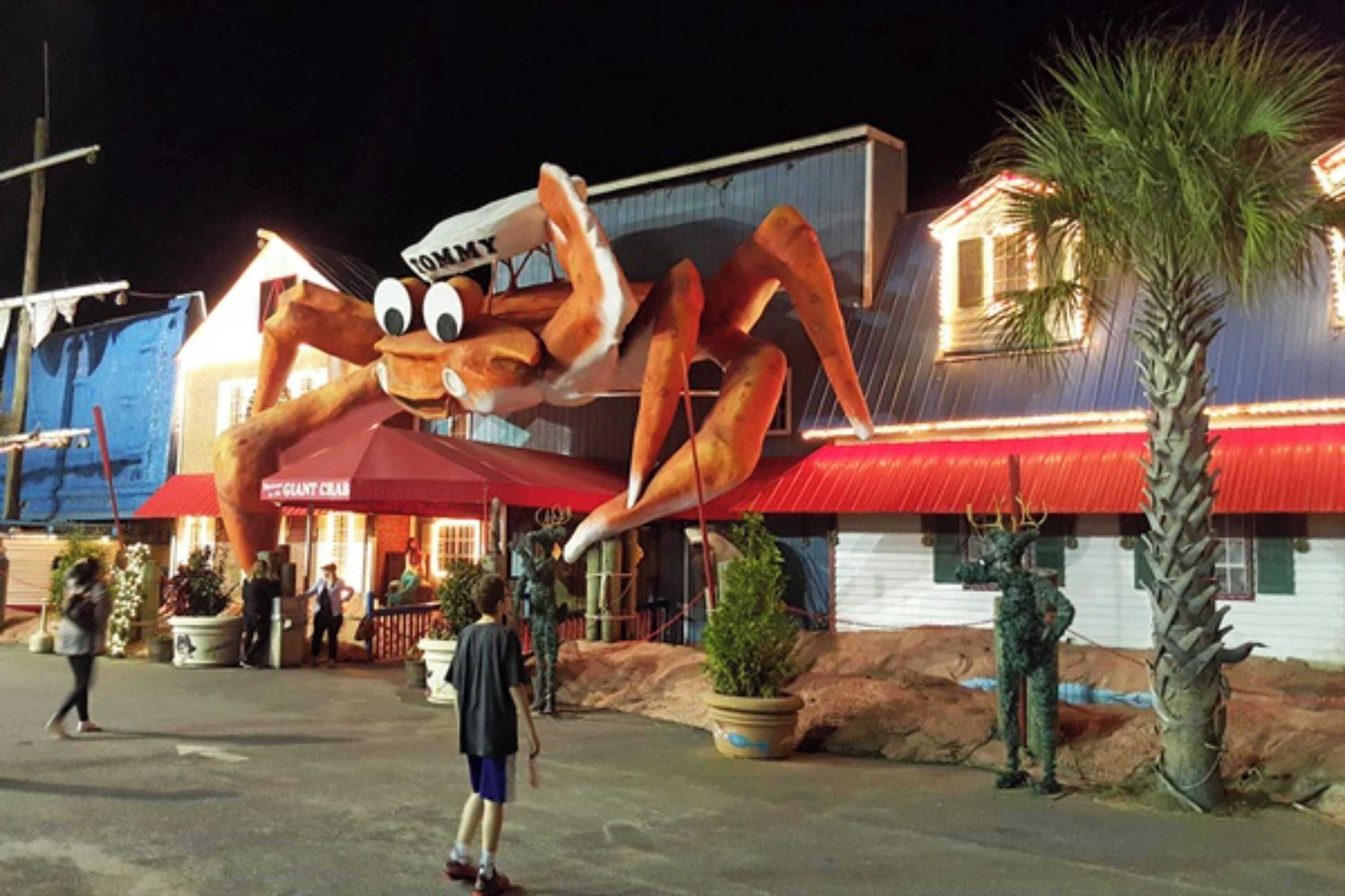 A large crab mascot outside a building with a red roof and a sign that reads "Giant Club."
