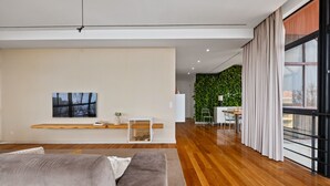Ein modernes Wohnzimmer mit großem Fenster, einer Couch, einem Flachbildfernseher und einer grünen Wand.