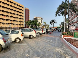 A parking area with several cars, a building with multiple balconies, and a sign for KSR Inmobiliaria. - Tropical Terraza a la Piscina (Playa del Inglés)