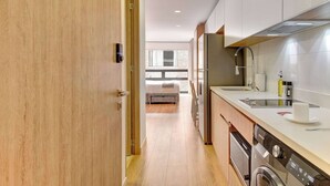 Eine moderne Küche mit Geschirrspüler, Spüle und Fensterblick auf ein Schlafzimmer.