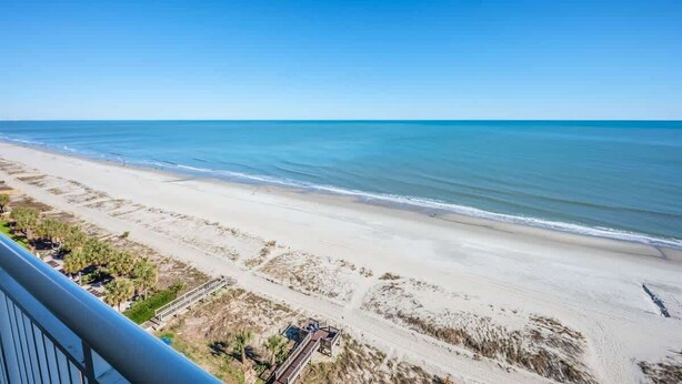 Une vue sur la plage depuis un balcon, avec un ciel dégagé.