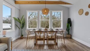 En matplats med ett träbord för fyra personer, omgiven av naturligt ljus som strömmar in genom stora fönster.