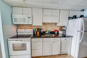 A kitchen with white cabinets, a microwave, stove, and a refrigerator. - High Floor, Direct Oceanfront Views,Camelot Resort (Myrtle Beach)