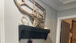 Un corridoio con una panca bianca, uno scaffale nero con oggetti decorativi e un punto luce a parete.