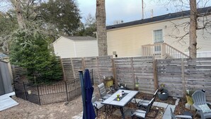 Un cortile con un tavolo da patio, sedie e una recinzione in legno.